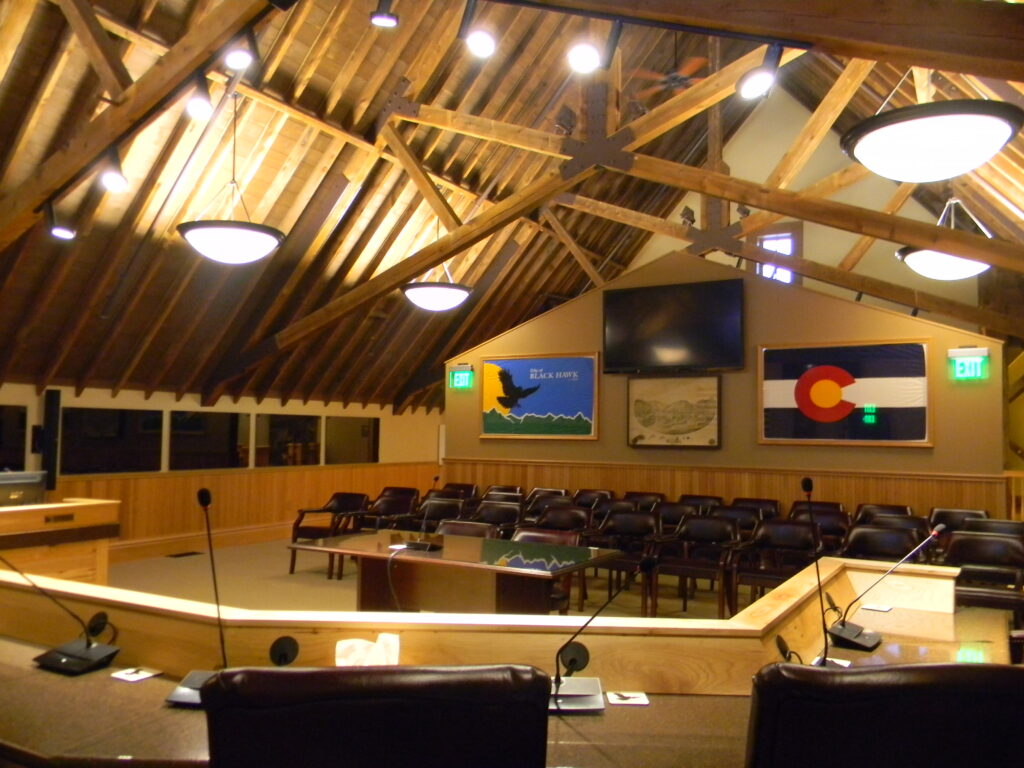 Civic building interior featuring exposed wood beams, timber ceiling structure, meeting chamber seating, and architectural design by PEH Architects in Boulder