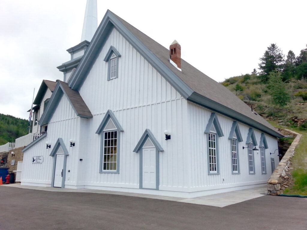 Historic church restoration featuring white siding, steep gable roof, decorative windows, and traditional architectural design by PEH Architects in Boulder