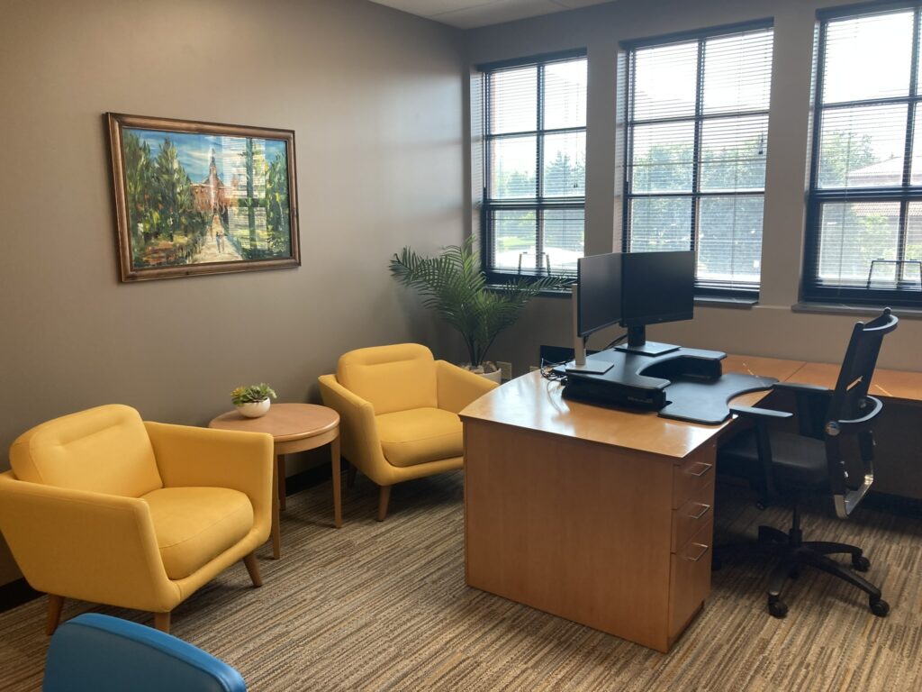 Modern Boulder office workspace featuring wooden desk, computer setup, yellow lounge chairs, large windows, and contemporary interior design by PEH Architects