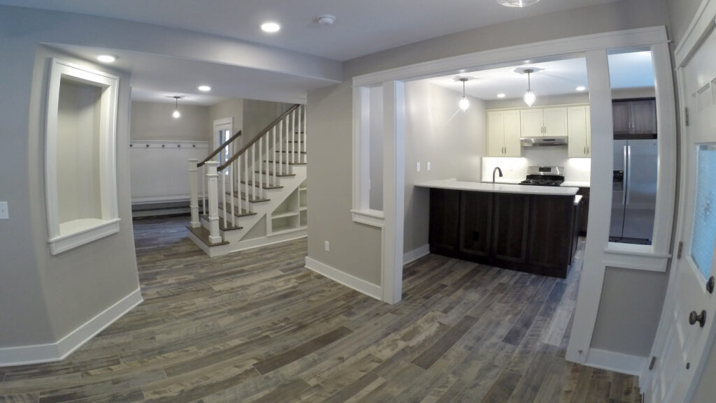 Open concept home renovation featuring modern kitchen, living area, staircase, wood flooring, and contemporary interior design by PEH Architects in Boulder