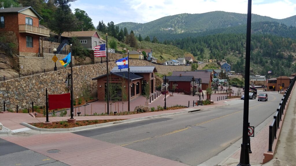 Historic mountain town streetscape featuring restored buildings, pedestrian walkways, stone walls, landscaping, and community-focused urban design