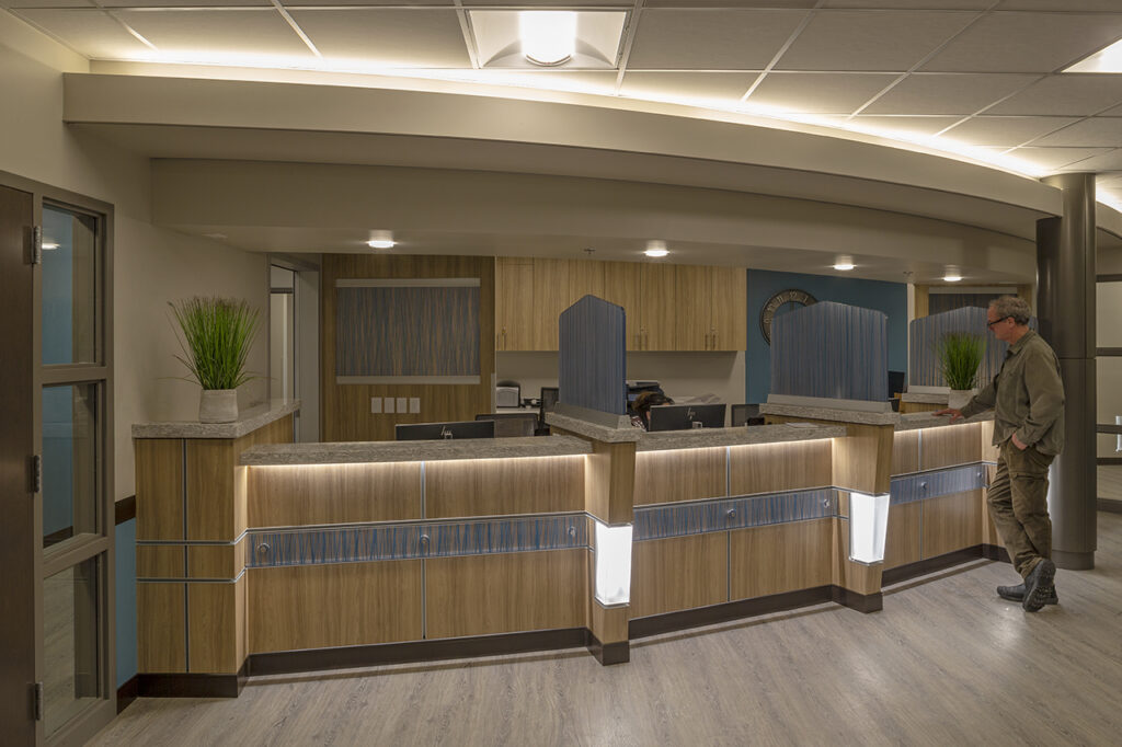 Modern healthcare nurses station featuring custom reception counters, wood finishes, lighting design, and efficient medical workspace layout