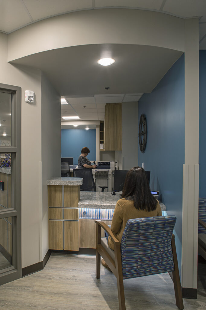 Modern healthcare patient check-in area featuring reception counter, seating space, workstations, and contemporary medical interior design