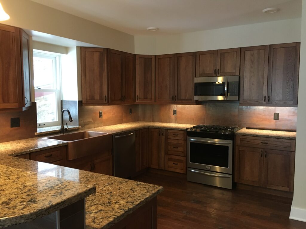 Modern kitchen renovation featuring custom wood cabinets, granite countertops, stainless steel appliances, and under cabinet lighting by PEH Architects