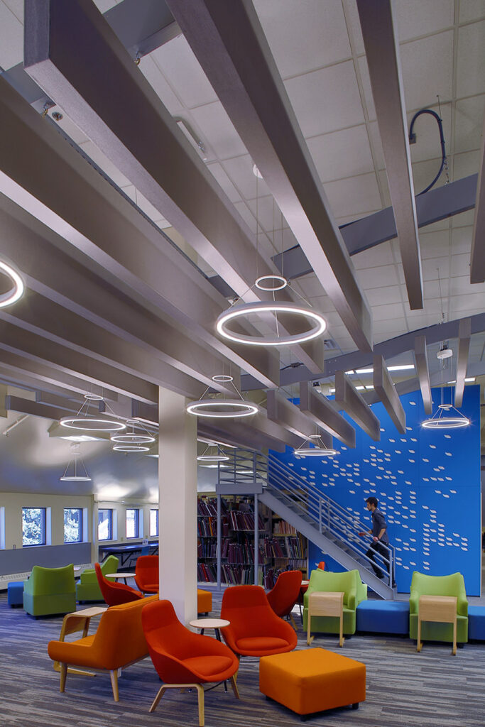 Contemporary library interior featuring colourful lounge seating, architectural ceiling design, modern lighting fixtures, bookshelves, and collaborative study areas by PEH Architects