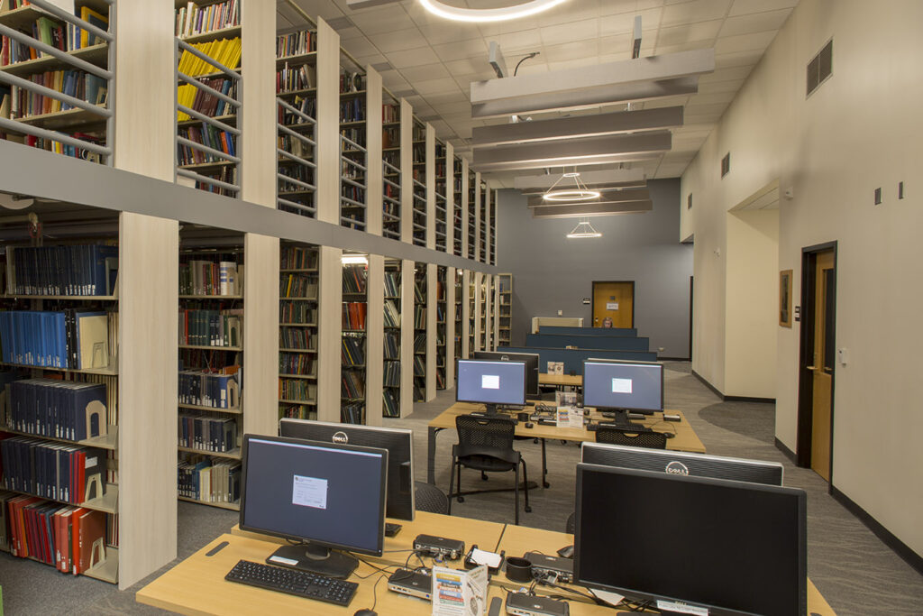 Modern library interior featuring computer workstations, tall bookshelves, study desks, and contemporary architectural design by PEH Architects