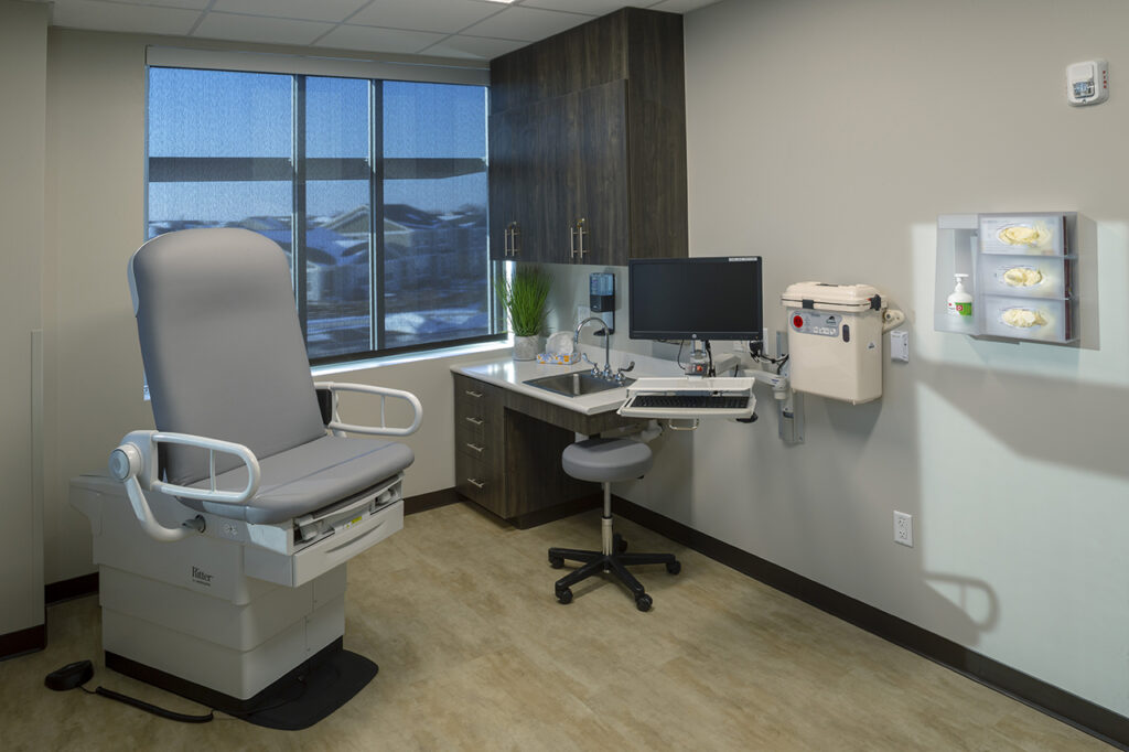 Modern medical examination room with patient exam chair, computer workstation, storage cabinets, and healthcare interior design