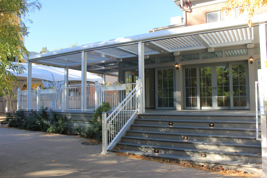 Modern covered patio with composite deck, wide stairs, white railings, and outdoor living area attached to home