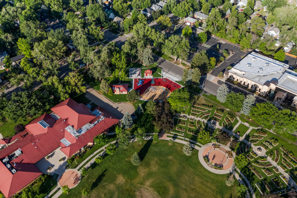 Aerial view of a civic park featuring landscaped gardens, walking paths, open green spaces, playgrounds, and surrounding neighborhood designed by PEH Architects in Boulder.