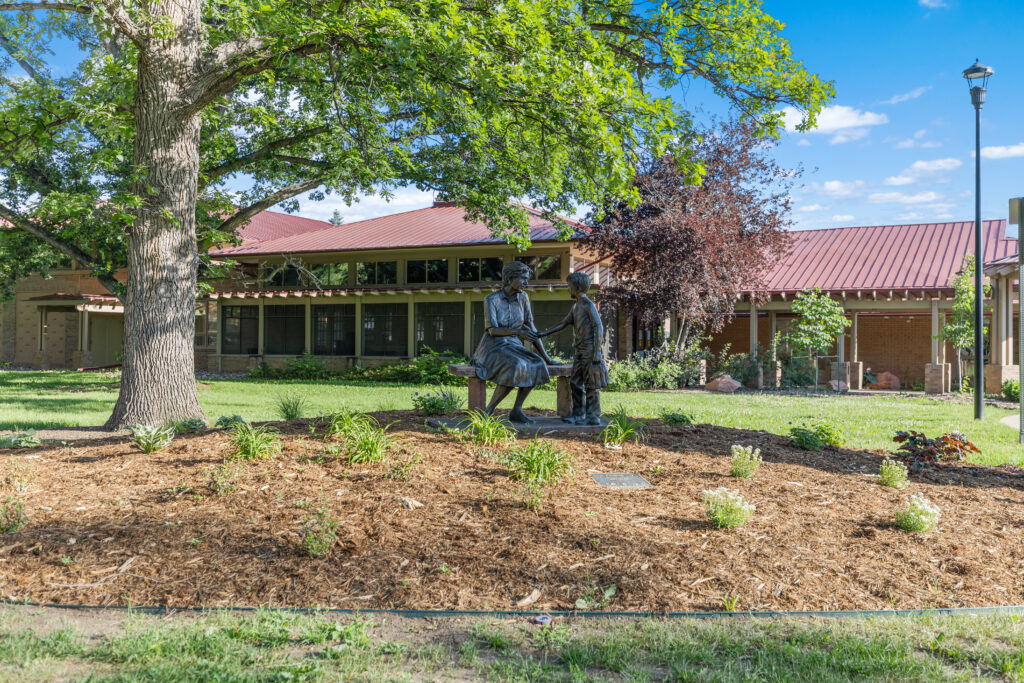 Community campus featuring landscaped grounds, mature trees, public artwork, and pedestrian-friendly outdoor spaces designed by PEH Architects in Boulder.