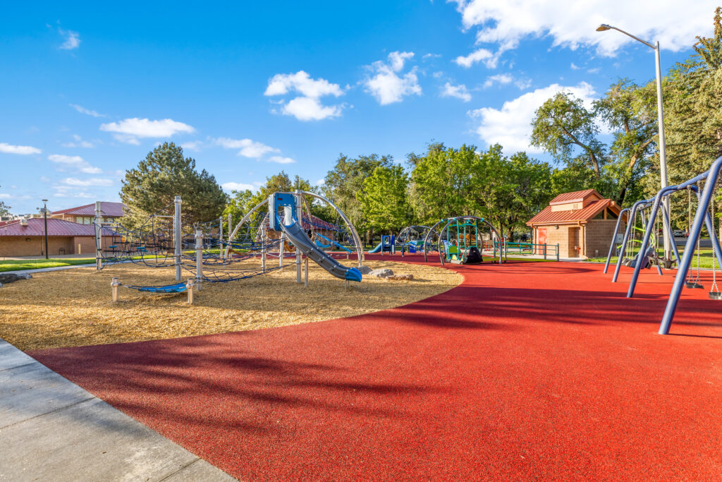 Community playground featuring modern play structures, swings, safety surfacing, and landscaped park areas designed by PEH Architects in Boulder.