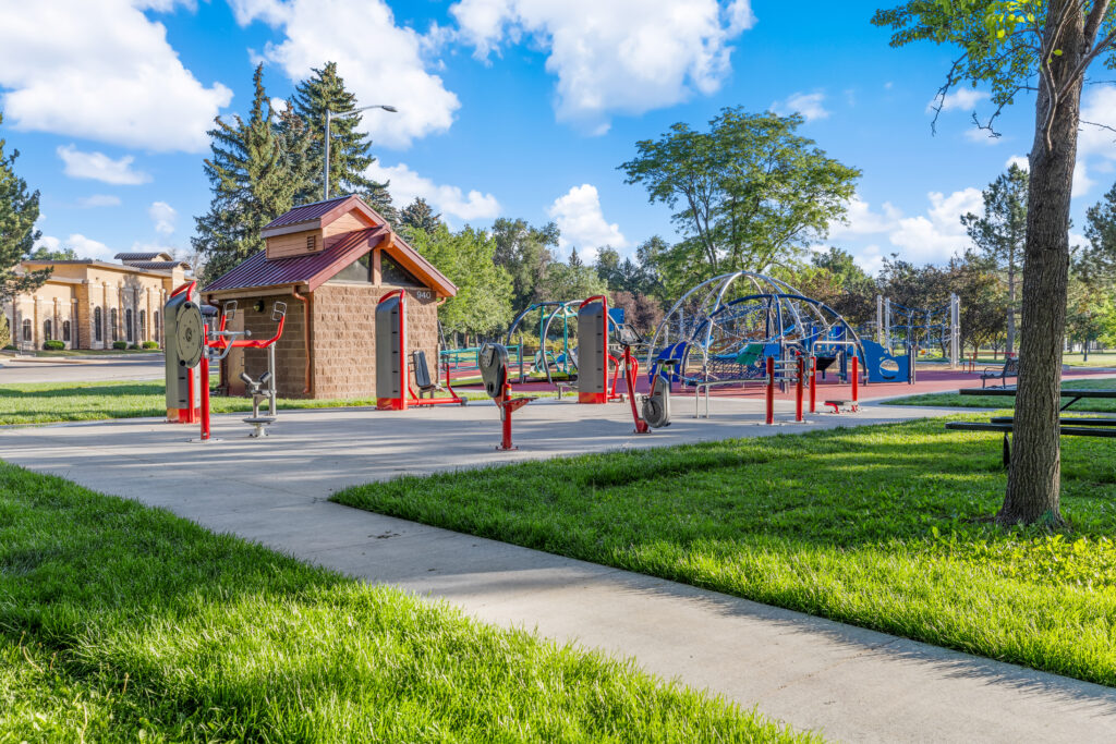 Outdoor fitness area with exercise equipment, accessible playground, walking paths, and landscaped community park designed by PEH Architects in Boulder.